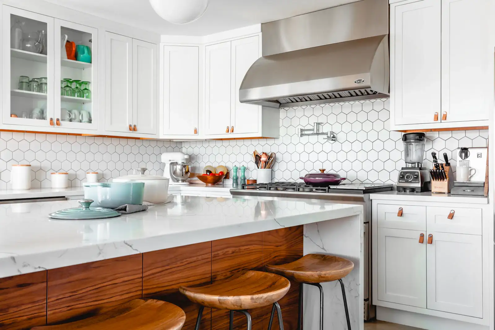 A white kitchen with a marble island and a range hood. Shown on the homepage for Boca Raton, FL.